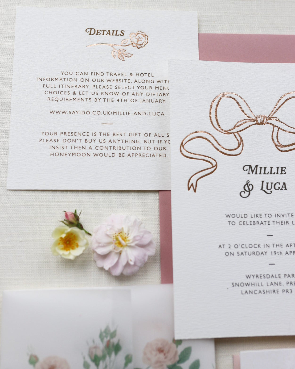 Bow Wedding Details Card featuring a rose steam, foiled onto thick textured card with couples names and information printed in a soft brown colour. Laid out flat lay style with invitation card and wild roses. Designed by Fancy Folk Wedding Stationery