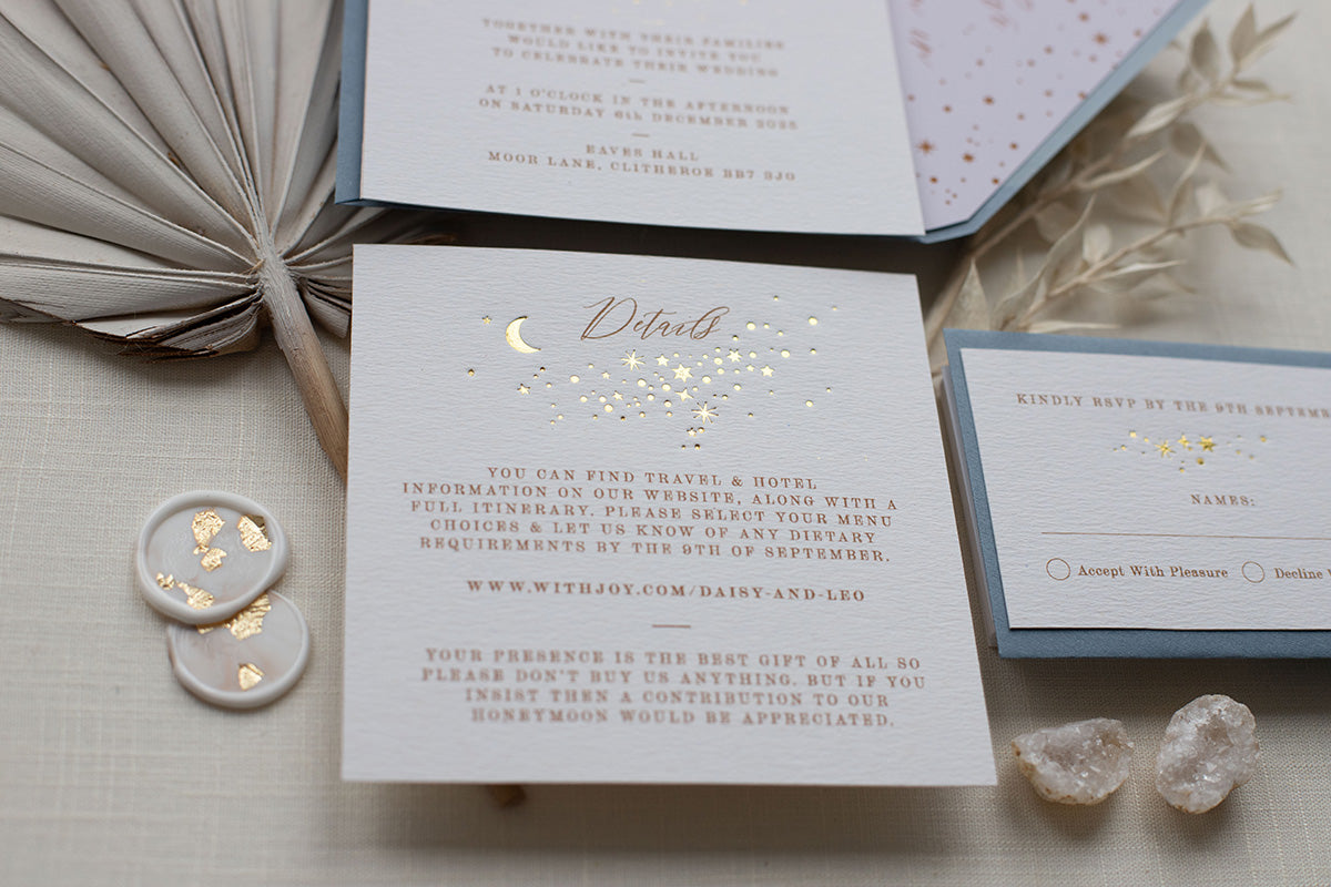 Celestial themed wedding details card. A truly magical design made up of lots of little stars is hot foiled in gold on to thick textured card. Styled with silk ribbon and dusty blue coloured envelopes and wax seals. FancyFolk Design