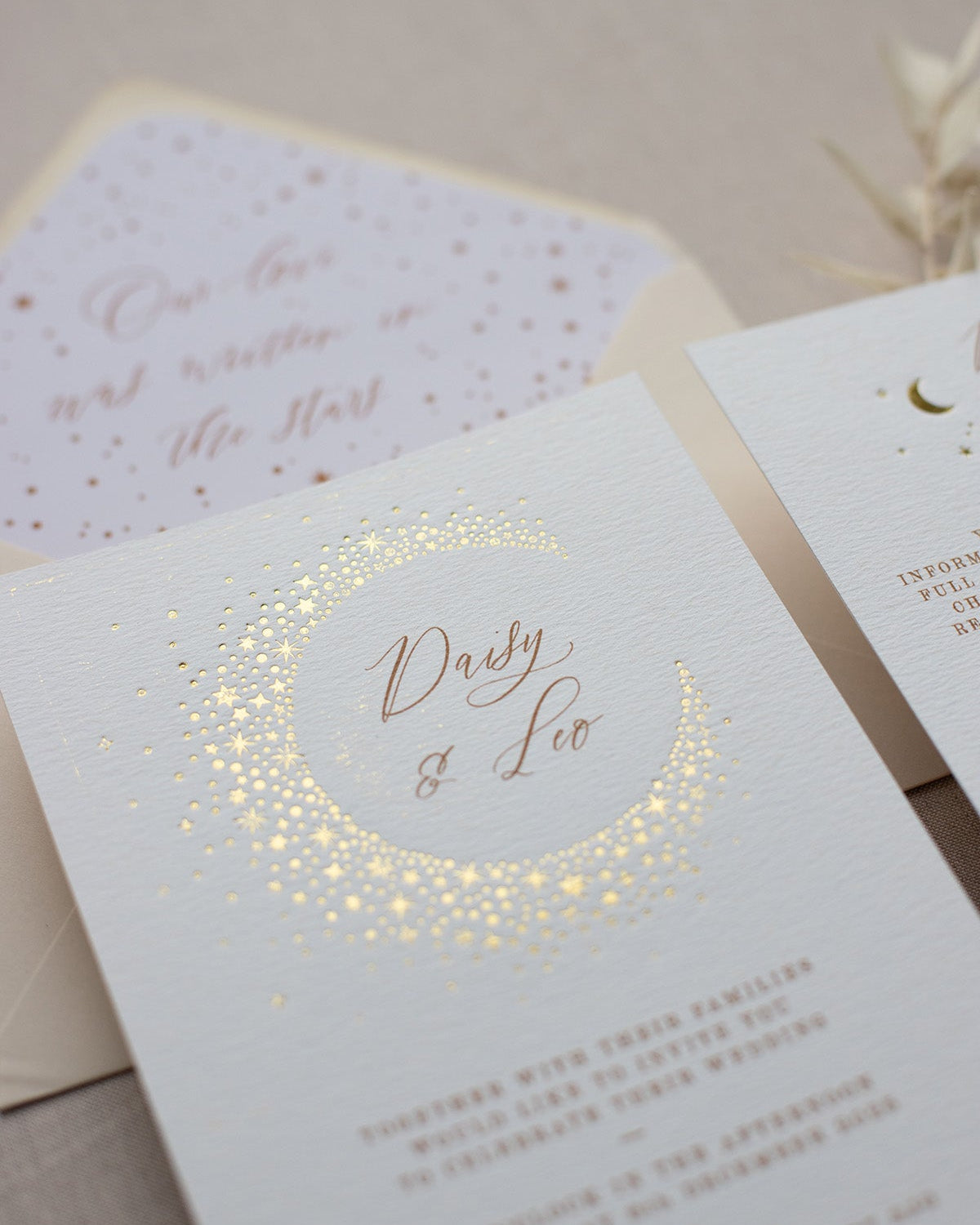 Celestial themed wedding invitation. A truly magical crescent moon design made up of lots of little stars is hot foiled in gold on to the main invitation. The invitations are foiled and printed onto thick textured card, styled with almond coloured envelopes. FancyFolk Design
