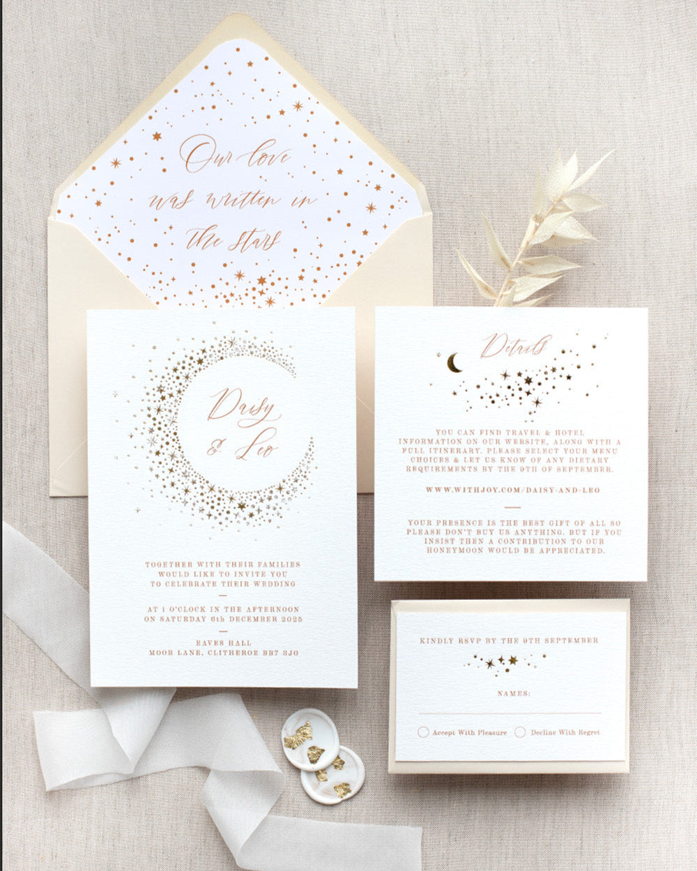Celestial themed wedding stationery suite laid out in a flat lay format. A truly magical crescent moon design made up of lots of little stars is hot foiled in gold on to the main invitation. Smaller cluster of gold stars feature on the details card and RSVP. The invitations are foiled and printed onto thick textured card, styled with silk ribbon, wax seals and almond coloured envelopes. FancyFolk Design