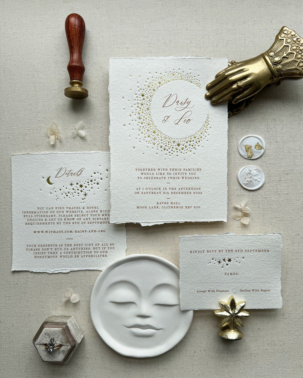 Celestial themed wedding stationery suite laid out in a flat lay format. A truly magical crescent moon design made up of lots of little stars is hot foiled in gold on to the main invitation. Smaller cluster of gold stars feature on the details card and RSVP. The invitations are foiled and printed onto tactile handmade paper with a torn romantic edge. FancyFolk Design
