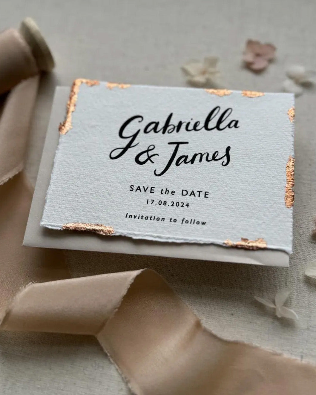 Wedding Save The Date. Beautiful calligraphy names read Gabriella & James with wedding date below. Printed onto tactile Indian handmade cotton paper. The cards have hand torn edges for a romantic feel with copper leaf accents which sparkle. Paired with a neutral almond coloured envelope. Fancy Folk