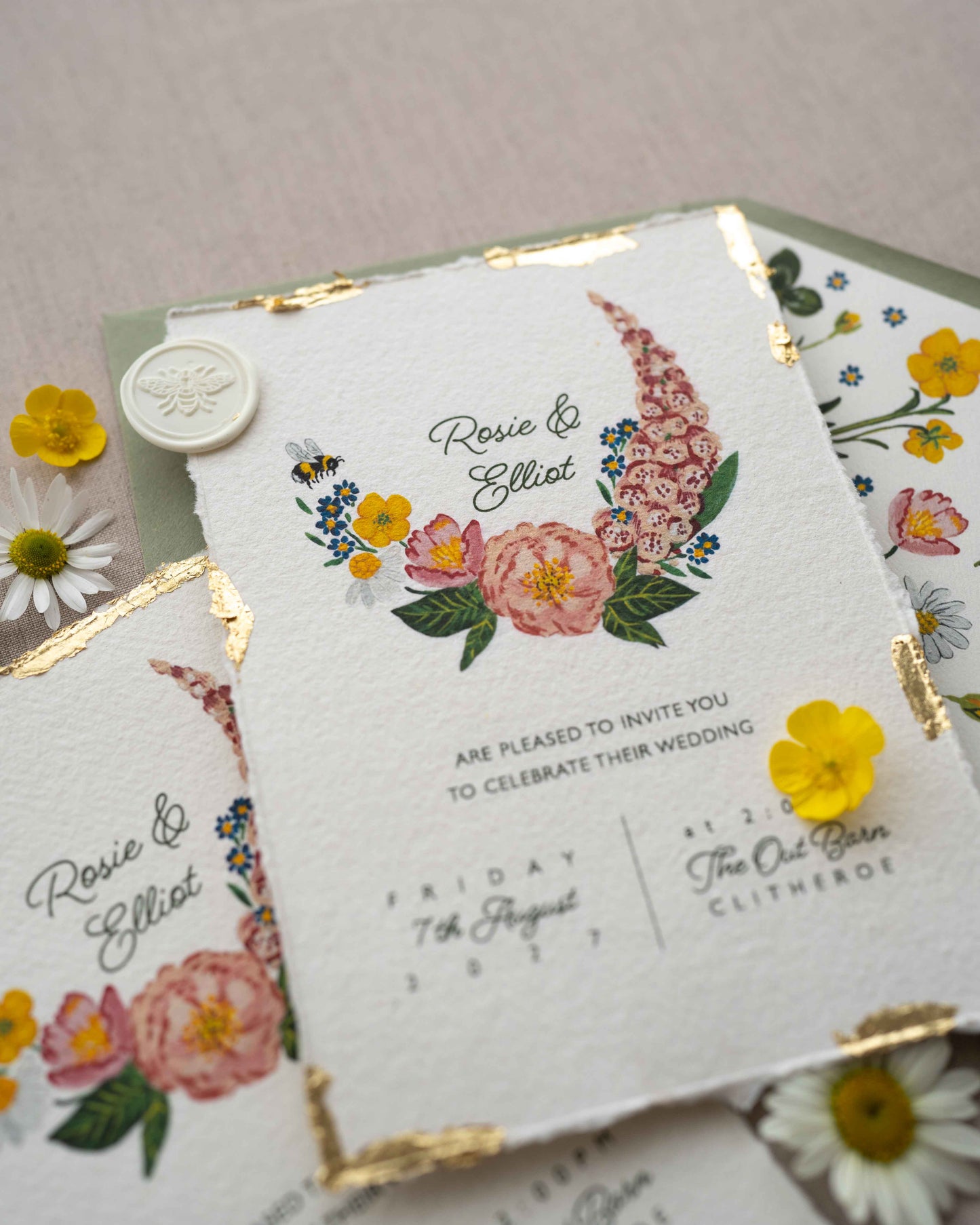 Watercolour hand painted florals of meadow flowers and a little bee make up a posy. Couples names are nestled in the floral. Printed on handmade Indian cotton paper with gold leaf accent. Styled with white bee wax seals, floral envelope liners and silk ribbon. Sage green envelopes and fresh flowers.