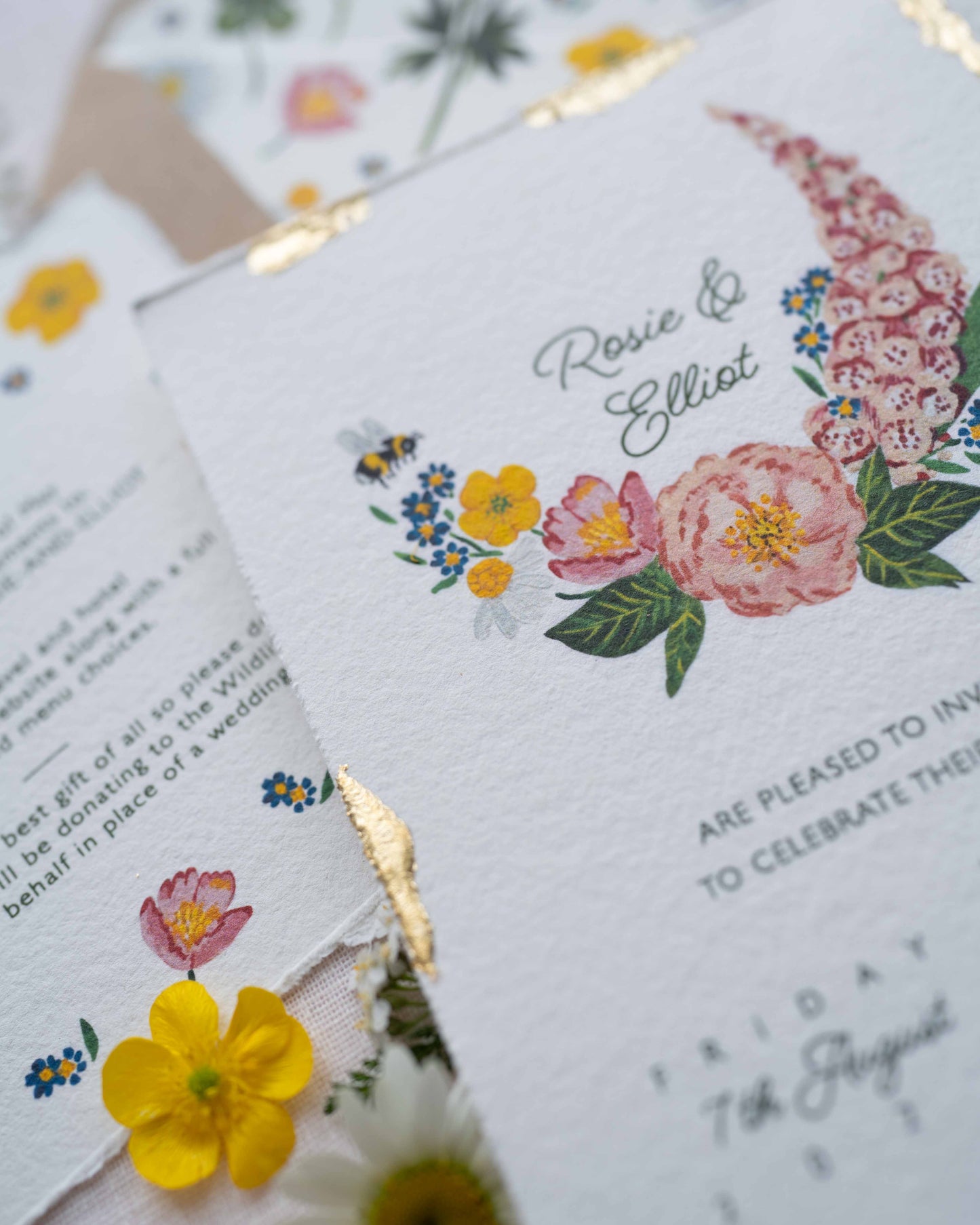 Close up of watercolour hand painted florals of meadow flowers and a little bee make up a posy. Couples names are nestled in the floral. Printed on handmade Indian cotton paper with gold leaf accent.