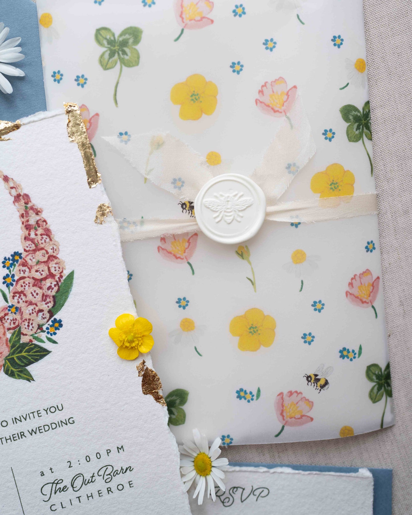 Wildflower vellum wrap features watercolour buttercups, bees, wild roses, forget me nots and daisies. The wrap houses all your paper elements neatly keeping them together. Tied with a silk ribbon and finished with a bee wax seal.