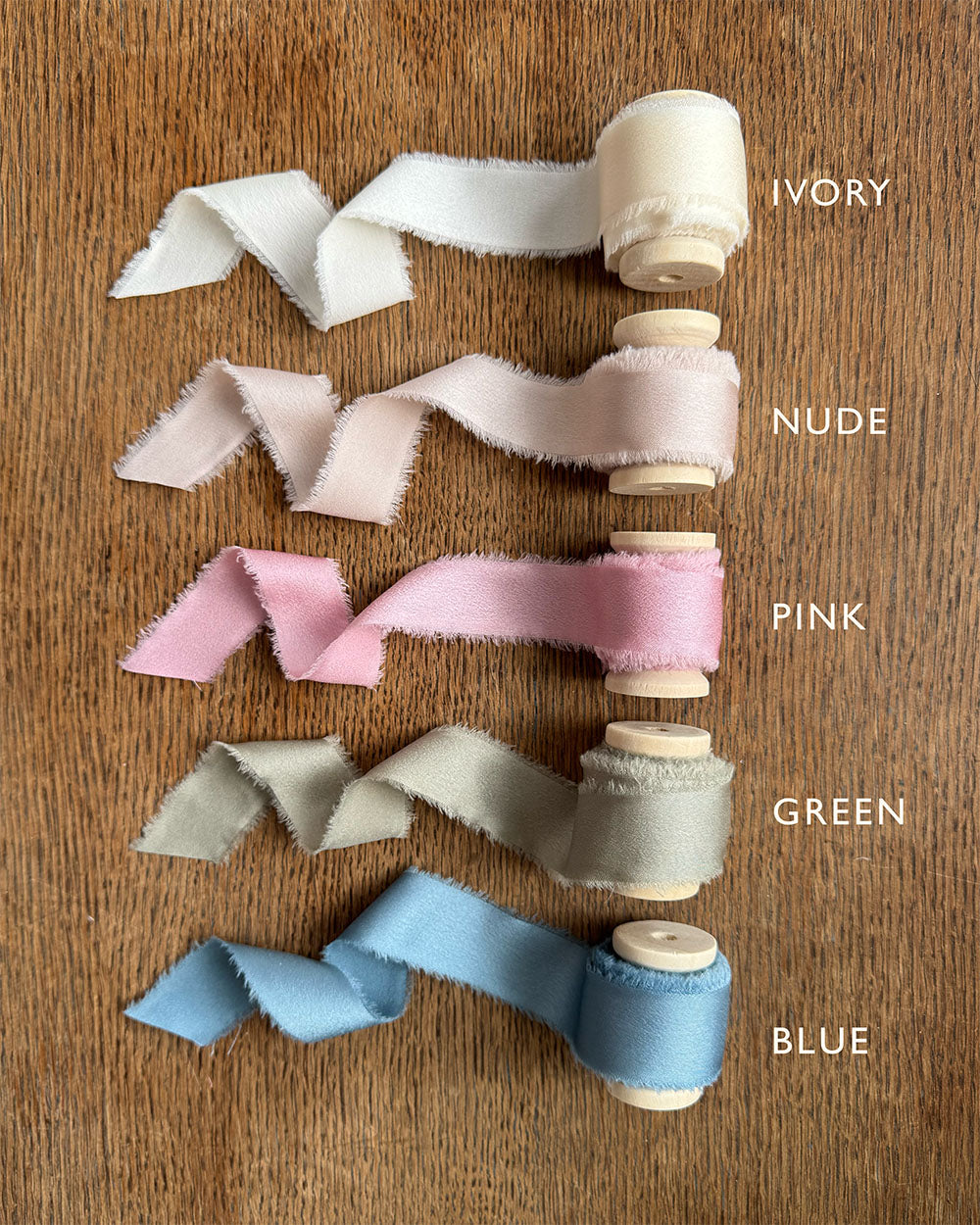Satin ribbon reels on wooden spools of various colours for wedding stationery. Ivory, Nude, Pink,. Green and Blue. Fancy Folk