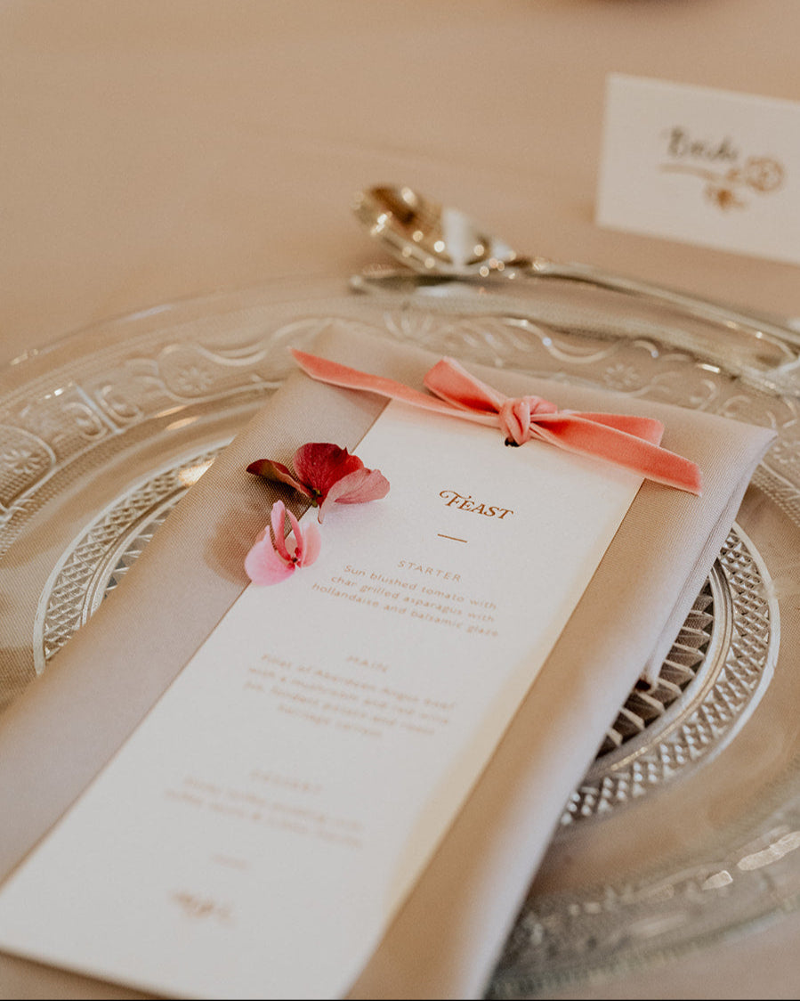 Blush velvet bow wedding breakfast menu place on a neutral napkin. Designed by Fancy Folk Wedding Stationery.