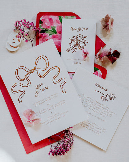 Bow Wedding Invitation featuring a large Rose Gold Bow Design, foiled onto  thick textured card with couples names and information printed in a soft brown colour. Paired with hot pink envelope with floral envelope liner, white wax seal with rose gold flakes. Laid out flat lay style with Details card and RSVP. Designed by Fancy Folk Wedding Stationery