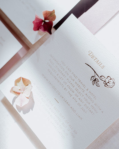 Close up of wedding details card featuring a foiled rose steam deign below the word 'Details'. Foiled onto  thick textured card with couples  information printed in a soft brown colour. Designed by Fancy Folk Wedding Stationery