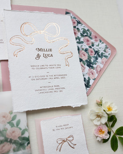 Rose Gold Bow Wedding Invitation. Paired with dusky pink coloured envelope and rose garden envelope liner. Printed on luxury hand made cotton paper with romantic hand torn edges. Designed by Fancy Folk Weddings
