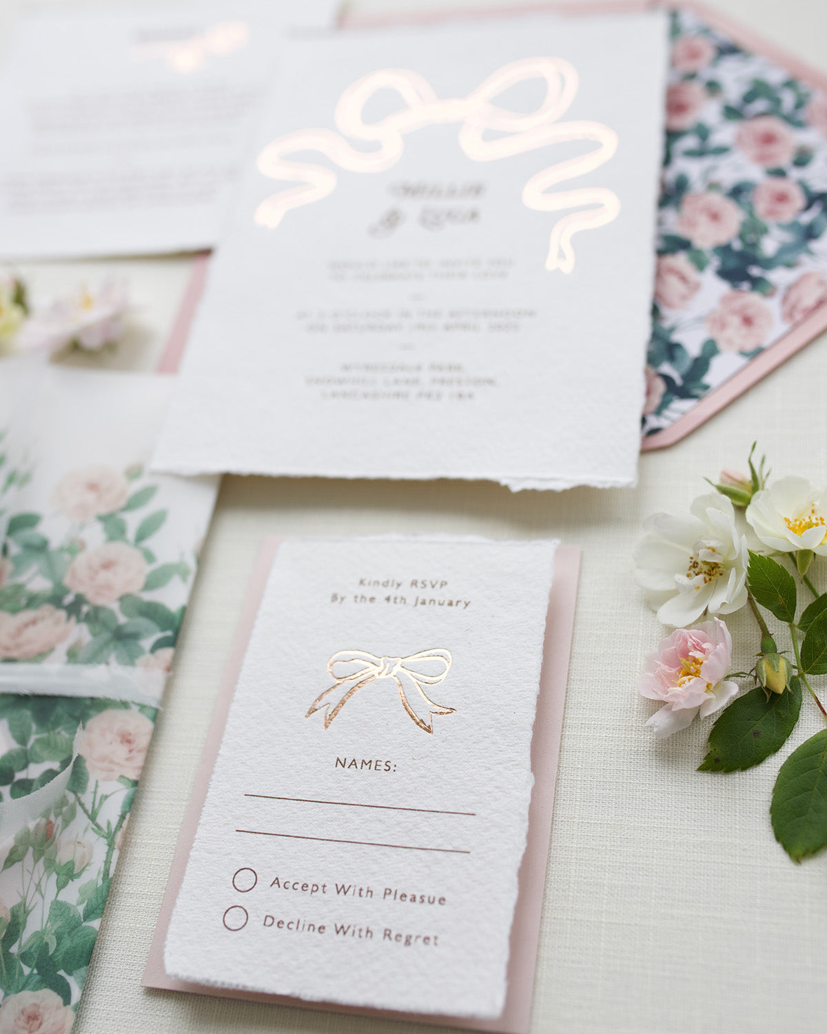 Close up of Rose gold Bow wedding RSVP card. Paired with blush pink coloured envelope. Printed on luxury hand made cotton paper with romantic hand torn edges. Designed by Fancy Folk Weddings