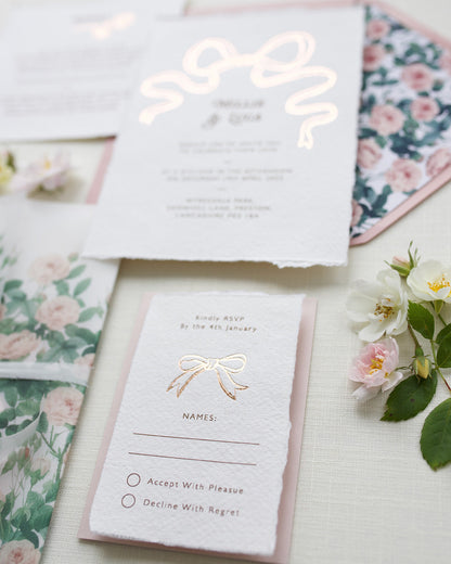 Close up of Rose gold Bow wedding RSVP card. Paired with blush pink coloured envelope. Printed on luxury hand made cotton paper with romantic hand torn edges. Designed by Fancy Folk Weddings