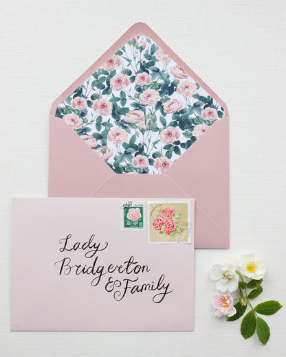 Hand Calligraphy Address written on a blush pink envelope. It reads "Lady Bridgerton & Family" styled with pink rose garden envelope liner. Fancy Folk Wedding Stationery