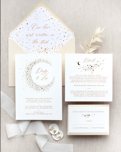 Celestial themed wedding stationery suite laid out in a flat lay format. A truly magical crescent moon design made up of lots of little stars is hot foiled in gold on to the main invitation. Smaller cluster of gold stars feature on the details card and RSVP. The invitations are foiled and printed onto thick textured card, styled with silk ribbon, wax seals and almond coloured envelopes. FancyFolk Design