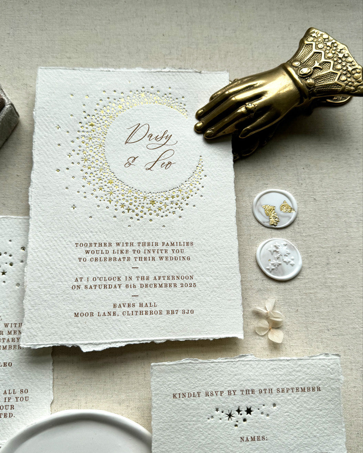 Celestial themed wedding invitation and almond coloured envelope. A truly magical crescent moon design made up of lots of little stars is hot foiled in gold on to tactile handmade paper with a torn romantic edge. The gold foil sparkles in the light. FancyFolk Design