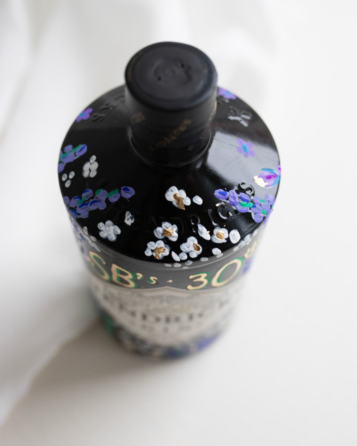 Hand painted occasion bottle. Blue and Purple Wildflowers which are embellished with gold leaf. Personalised initials and dates.