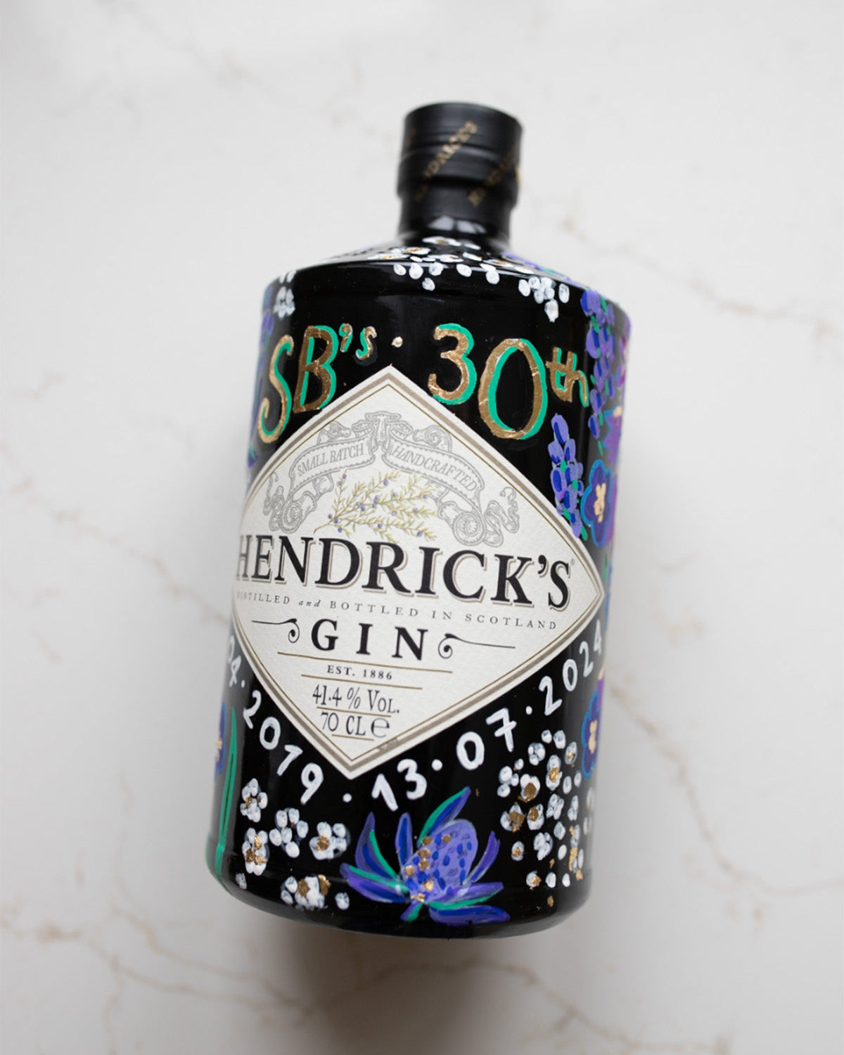 Hand painted occasion bottle. Blue and Purple Wildflowers which are embellished with gold leaf. Personalised initials and dates.