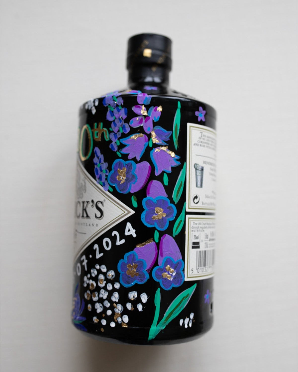 Hand painted occasion bottle. Blue and Purple Wildflowers which are embellished with gold leaf. Personalised initials and dates.