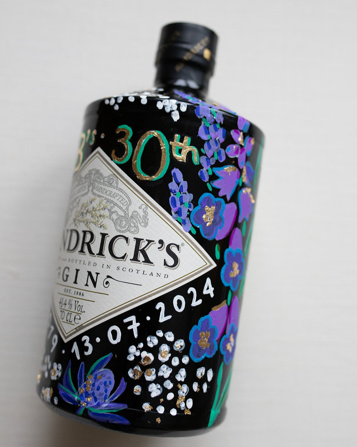Hand painted occasion bottle. Blue and Purple Wildflowers which are embellished with gold leaf. Personalised initials and dates.