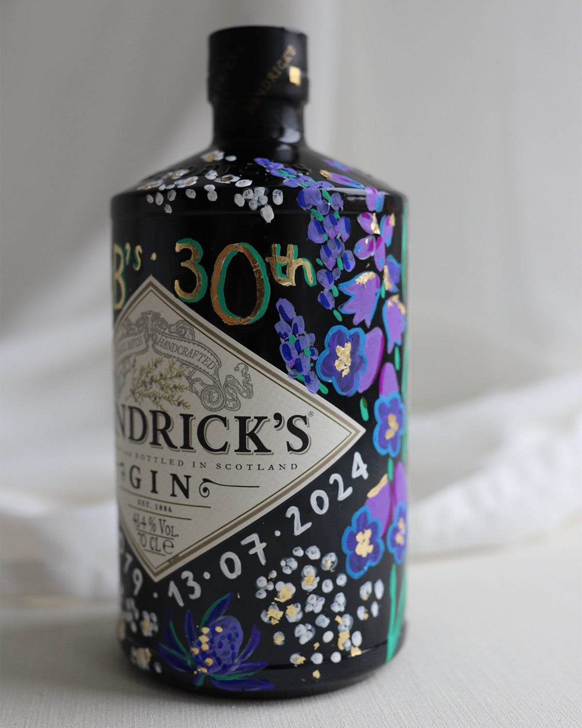 Hand painted occasion bottle. Blue and Purple Wildflowers which are embellished with gold leaf. Personalised initials and dates.
