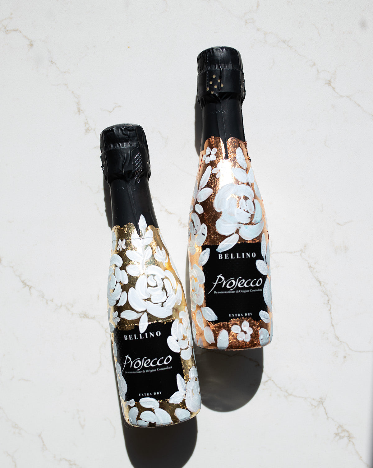 Mini bottles of Prosecco hand painted with a white roses design on a metallic gold and copper leaf base. The perfect luxury bridesmaid proposal gift. Paired with a pink roses panted design available in a separate listing. Fancy Folk Design