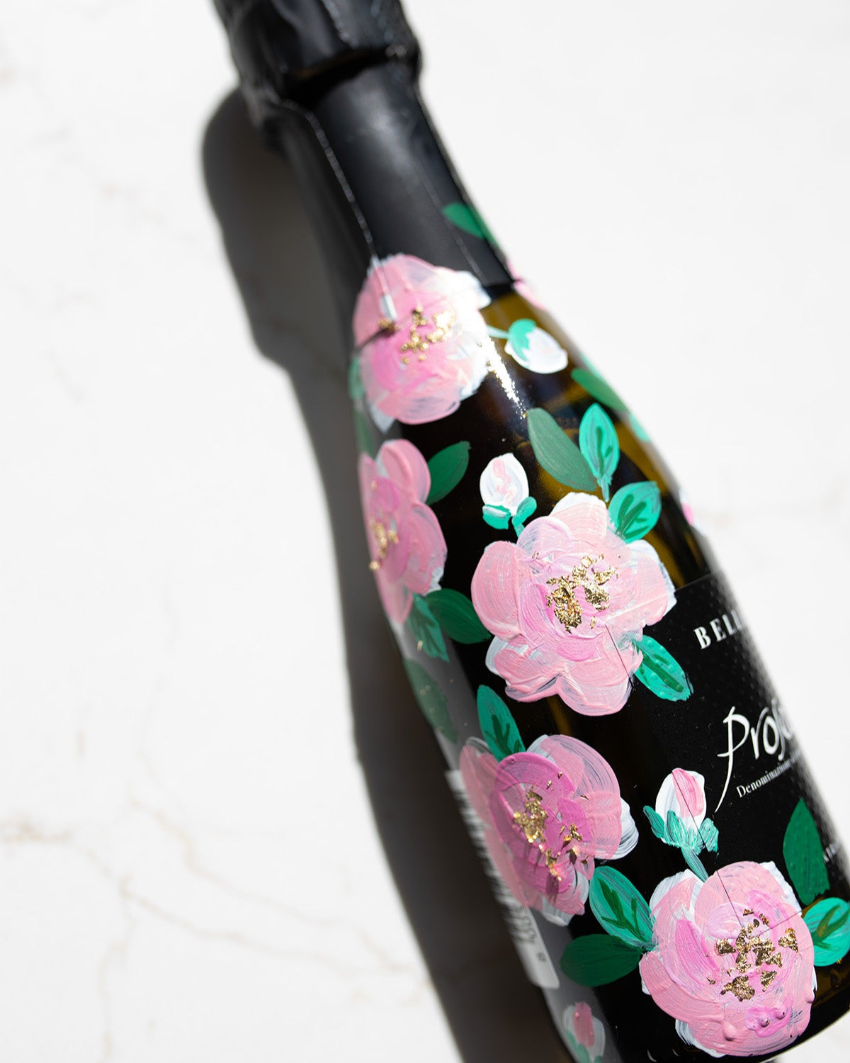 Hand painted pink roses with gold leaf accents in the centres. Painted onto mini bottles of Prosecco. a perfect bridesmaids proposal gift. Fancy Folk Design