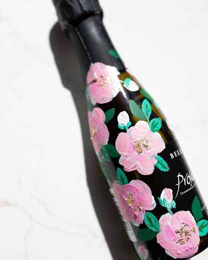 Hand painted pink roses with gold leaf accents in the centres. Painted onto mini bottles of Prosecco. a perfect bridesmaids proposal gift. Fancy Folk Design