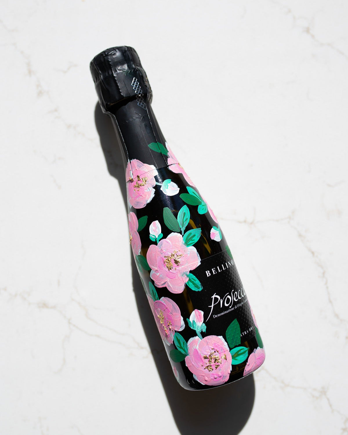 Hand painted pink roses with gold leaf accents in the centres. Painted onto mini bottles of Prosecco. a perfect bridesmaids proposal gift. Fancy Folk Design