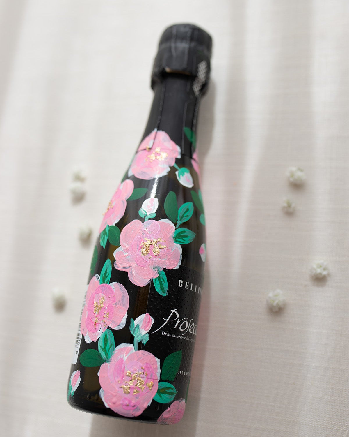 Hand painted pink roses with gold leaf accents in the centres. Painted onto mini bottles of Prosecco. a perfect bridesmaids proposal gift. Fancy Folk Design