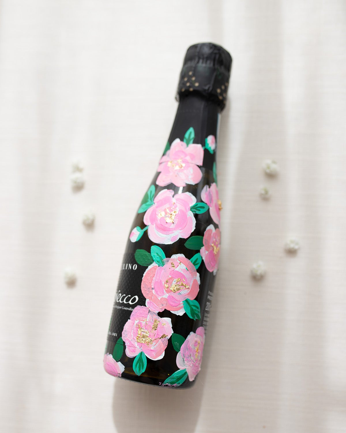 Hand painted pink roses with gold leaf accents in the centres. Painted onto mini bottles of Prosecco. a perfect bridesmaids proposal gift. Fancy Folk Design