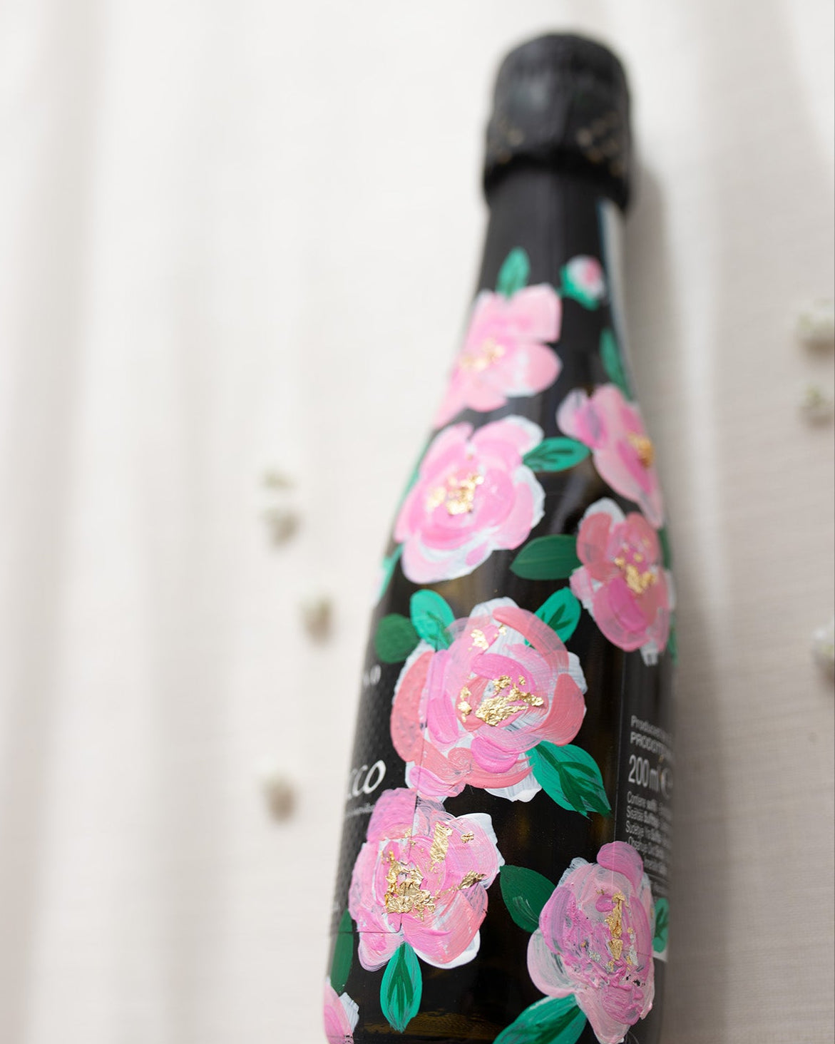 Hand painted pink roses with gold leaf accents in the centres. Painted onto mini bottles of Prosecco. a perfect bridesmaids proposal gift. Fancy Folk Design