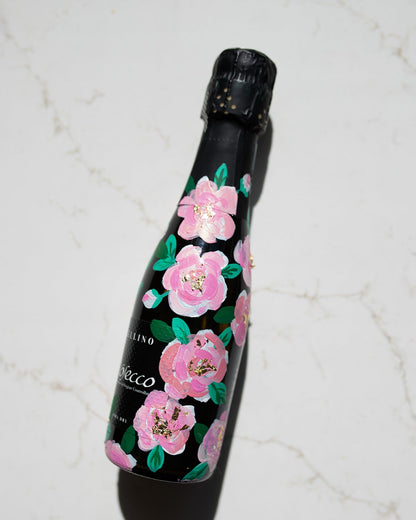 Hand painted pink roses with gold leaf accents in the centres. Painted onto mini bottles of Prosecco. a perfect bridesmaids proposal gift. Fancy Folk Design