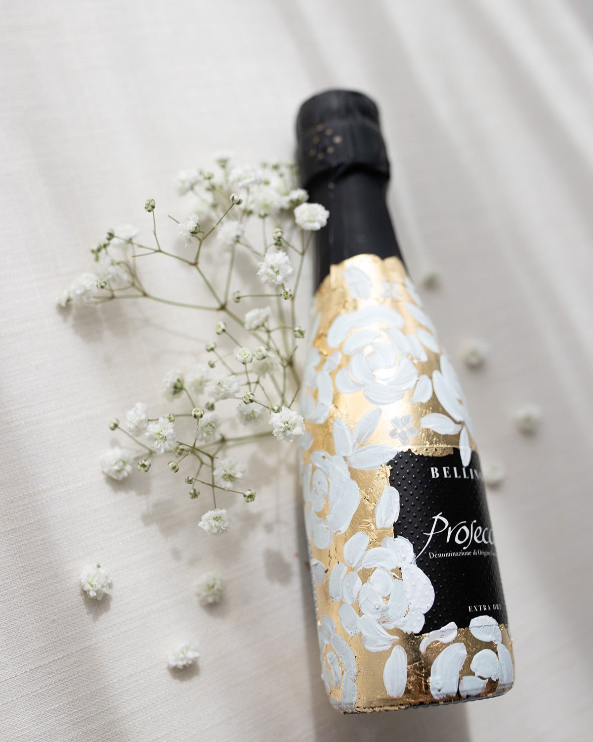 Mini bottles of Prosecco hand painted with a white roses design on a metallic gold base. The perfect luxury bridesmaid proposal gift. Fancy Folk Design