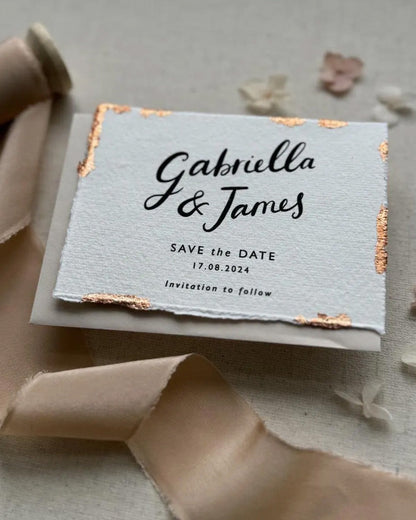 Wedding Save The Date. Beautiful calligraphy names read Gabriella & James with  wedding date below. Printed onto tactile Indian handmade cotton paper. The cards have hand torn edges for a romantic feel with copper leaf accents which sparkle.  Paired with a neutral almond coloured envelope. Fancy Folk