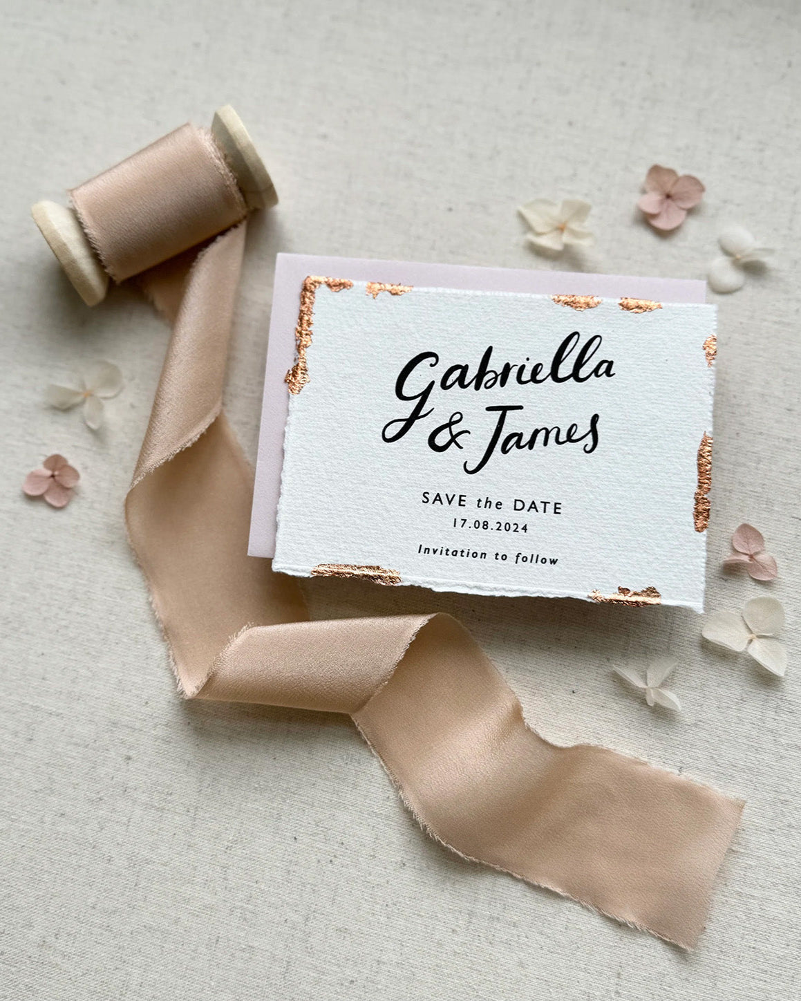Wedding Save The Date. Beautiful calligraphy names read Gabriella & James with  wedding date below. Printed onto tactile Indian handmade cotton paper. The cards have hand torn edges for a romantic feel with copper leaf accents which sparkle.  Paired with a blush pink coloured envelope. Fancy Folk
