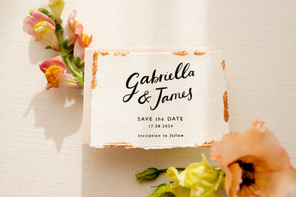 Wedding Save The Date. Beautiful calligraphy names read Gabriella & James with  wedding date below. Printed onto tactile Indian handmade cotton paper. The cards have hand torn edges for a romantic feel with copper leaf accents which sparkle.  Paired with a almond coloured envelope. Fancy Folk