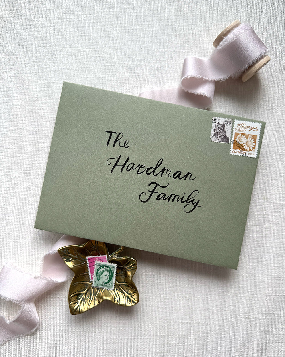 Wedding envelope calligraphy names and address in a black ink. Written on a sage green envelope. Fancy Folk