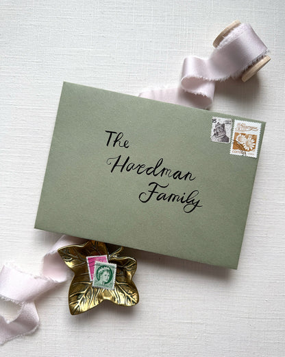 Wedding envelope calligraphy names and address in a black ink. Written on a sage green envelope. Fancy Folk