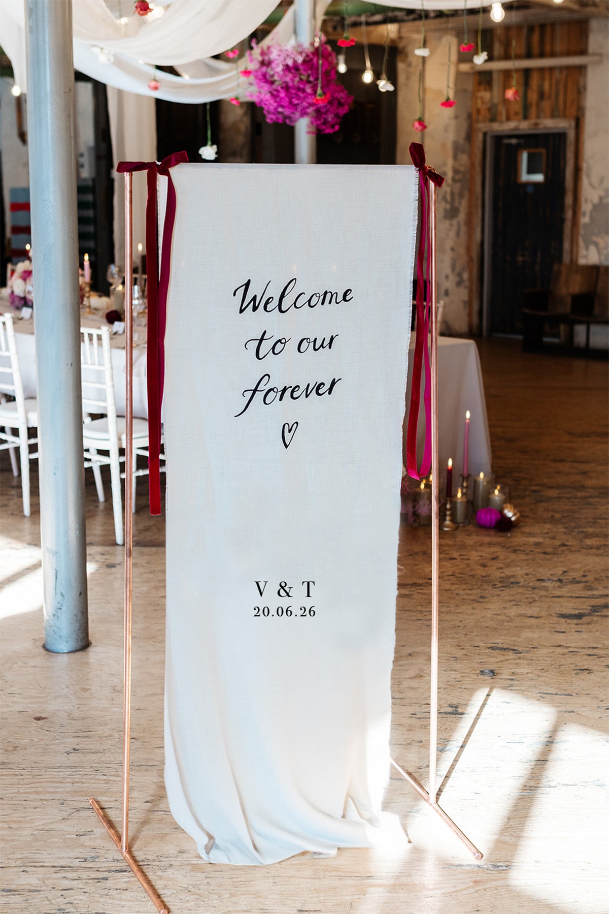 Fabric wedding welcome sign, hand painted quote in a modern calligraphy style onto a neutral cotton linen fabric. Couples initials and wedding date.
Hanging from a copper frame with velvet ribbon bows either side to greet your wedding guests. Fancy Folk