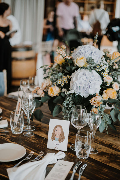 Illustrated wedding portrait used as a table place card. Surrounded by florals. Fancy Folk.