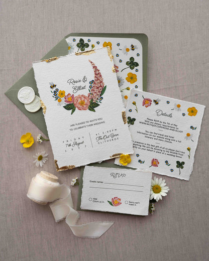 Watercolour hand painted florals of meadow flowers and a little bee make up a posy. Couples names are nestled in the floral. Printed on handmade Indian cotton paper with gold leaf accent. Styled with white bee wax seals, floral envelope liners and silk ribbon. Sage green envelopes and fresh flowers.