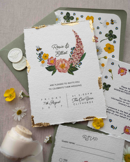 Watercolour hand painted florals of meadow flowers and a little bee make up a posy. Couples named are nestle in the floral. Printed on handmade Indian cotton paper with gold leaf accent. Styled with white bee wax seals, floral envelope liners and silk ribbon. Sage green envelops and fresh flowers.