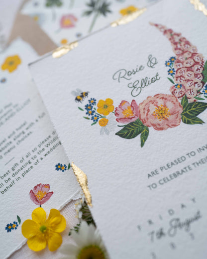 Close up of watercolour hand painted florals of meadow flowers and a little bee make up a posy. Couples names are nestled in the floral. Printed on handmade Indian cotton paper with gold leaf accent. 