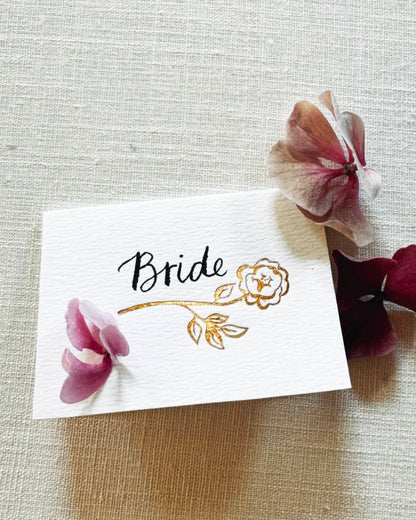 Foiled rose design place card for your wedding table with hand calligraphy bride. Rose Gold hot foil on textured card.  Designed by Fancy Folk wedding stationery