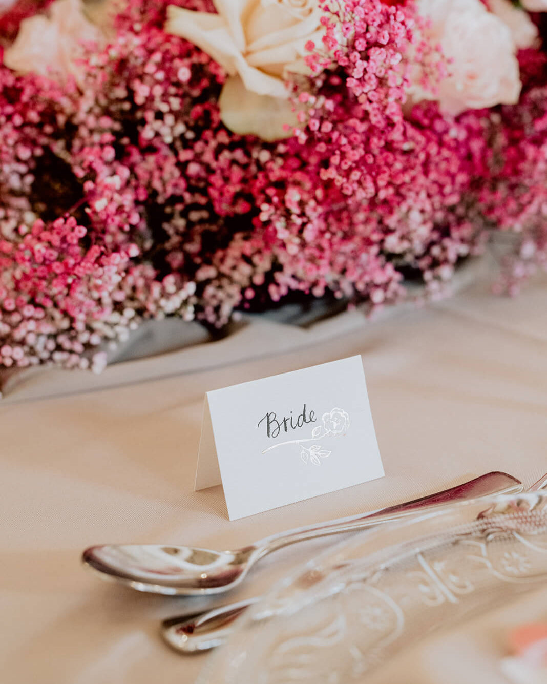 Foiled rose design place card for your wedding table with hand calligraphy bride text. Hot pink floral table centres. Designed by Fancy Folk wedding stationery.