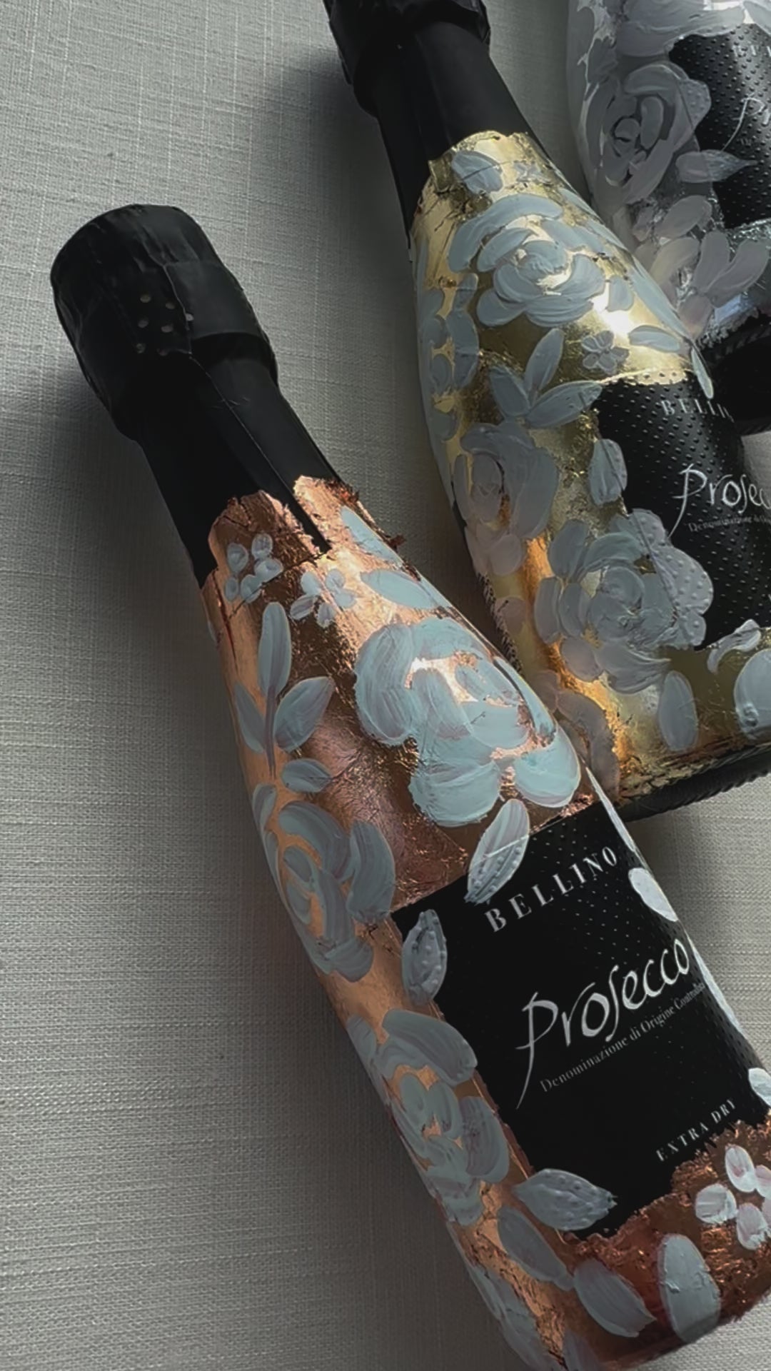 Mini bottles of Prosecco hand painted with a white roses design on a metallic base. Gold, silver and copper examples of the same design. The perfect luxury bridesmaid proposal gift. Fancy Folk Design